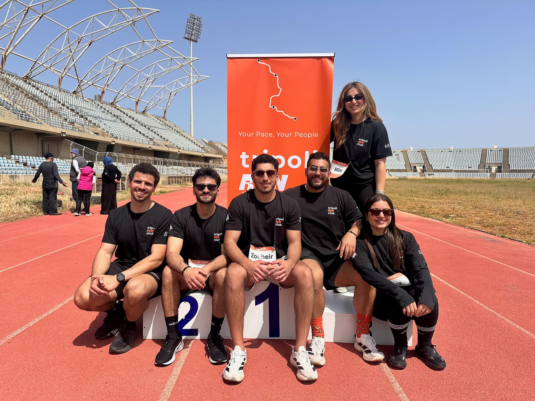 TRC team posing at the stadium track with the club banner